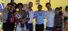 Prefeito, vice e secretária posam para foto com família beneficiada pelo programa - Foto de Roberto Ribeiro
